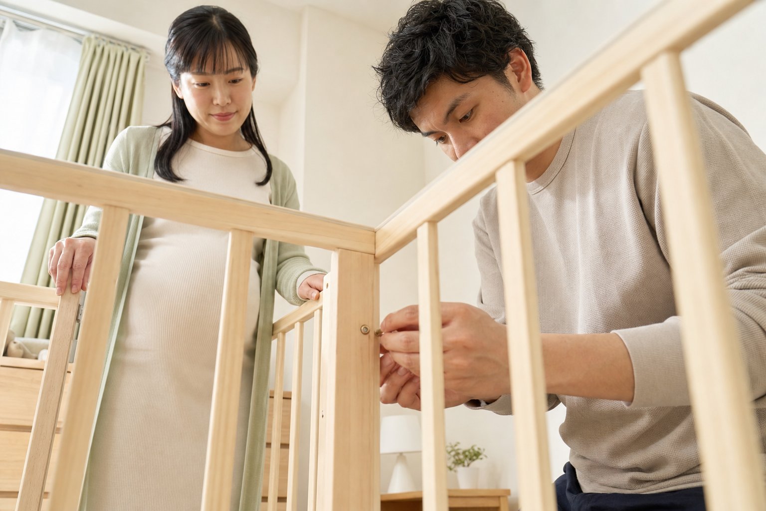 妊婦の女性と男性が木製ベッドの柵をネジで組み立てている